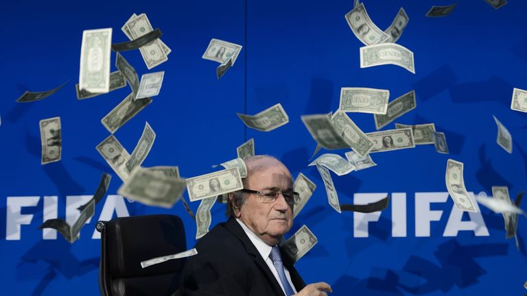 FIFA president Sepp Blatter looks on with fake dollars flying around him 