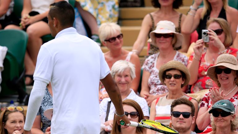 Nick Kyrgios is handed back his racquet by a member of the crowd during his match against Richard Gasquet during day seven of Wimbledon