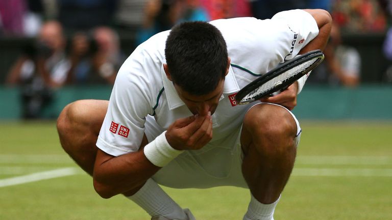 Novak Djokovic eats the centre court grass after winning against Roger Federer at Wimbledon
