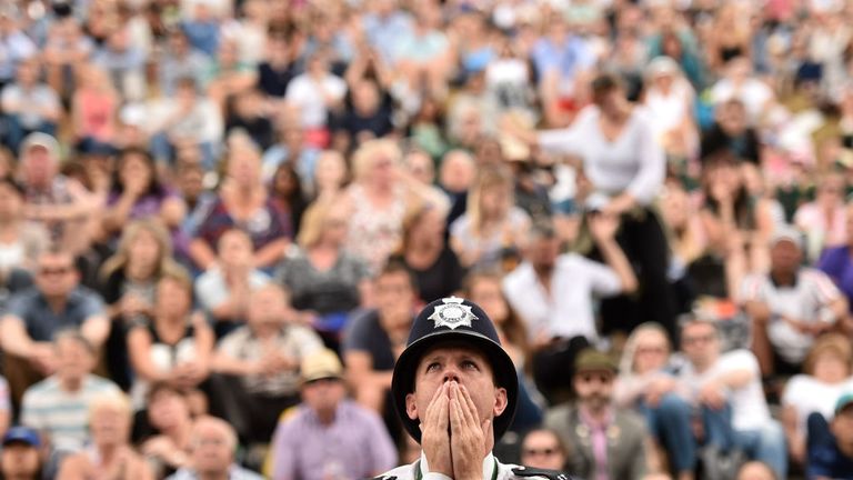 A British police officer reacts as he watches a giant screen showing the second set tie-break in the final between Novak Djokovic and Roger Federer