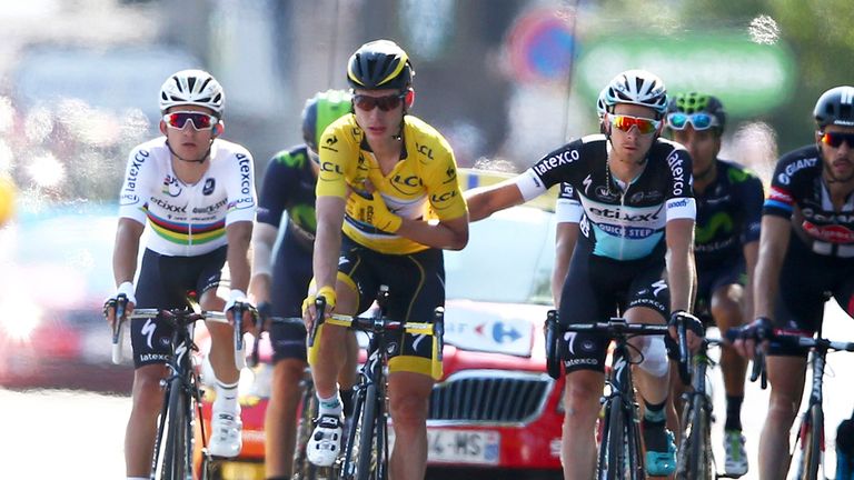 Teammates push Germany's Tony Martin who holds his arm in a position which could indicate a broken collar bone