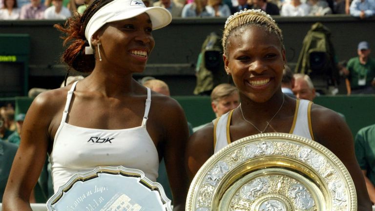 Serena Williams (R) holds the trophy after winning the Women's final against her sister Venus (L) at Wimbledon in 2002
