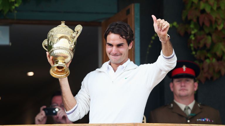 Roger Federer of Switzerland holds up the winner's trophy and gives a thumbs up to the crowd after winning his Gentlemen's Singles at Wimbledon