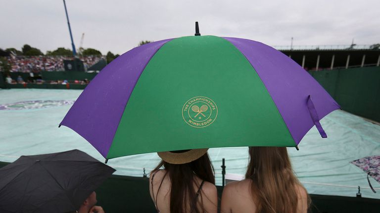 Spectators cover up from the rain during day four of the Wimbledon Championships at the All England Lawn Tennis and Croquet Club, Wimbledon.