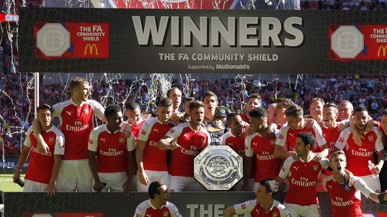 Arsenal's French manager Arsene Wenger (R) and his players celebrate with the trophy after beating Chelsea in 