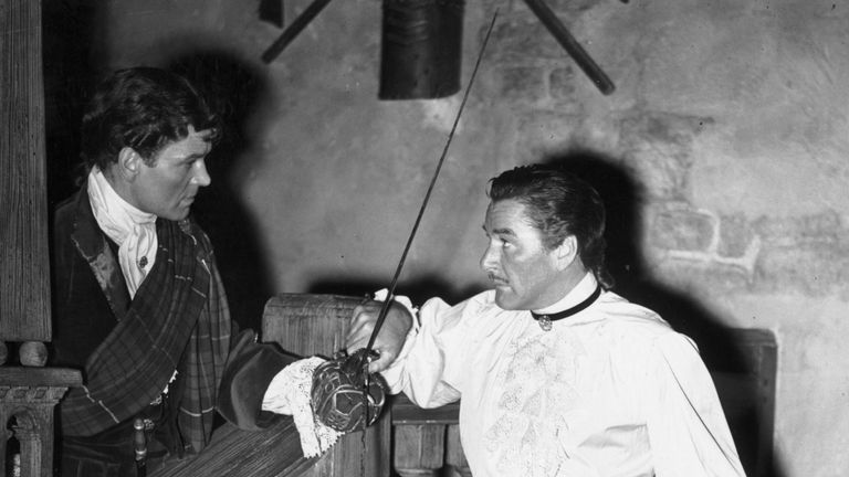 Anthony Steel (1920 - 2001) left, playing opposite American film star Errol Flynn (1909 - 1959) in a fencing scene, from the film version of Robert Louis S