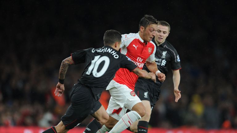 Mesut Ozil bursts between Philippe Coutinho and Jordan Rossiter of Liverpool.