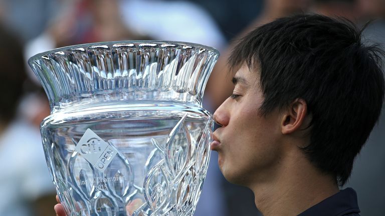Kei Nishikori of Japan celebrates with the trophy after defeating John Isner in Washington