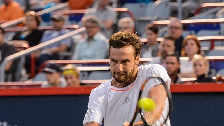 Ernests Gulbis hits a return against Novak Djokovic at the Montreal Masters