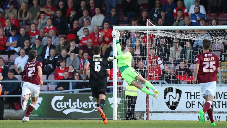 Adam Smith of Northampton dives in vain as he is beaten by a free-kick taken by Dean Cox of Leyton Orient