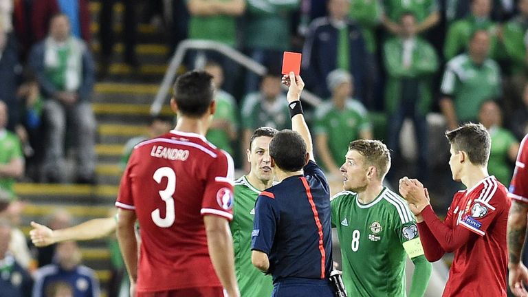 Northern Ireland defender Chris Baird (2nd L) receives a red card from referee Cuneyt Cakir v Hungary at Windsor Park in Belfast