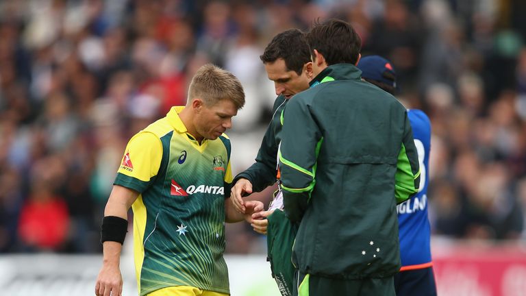 David Warner of Australia receives treatment on his hand after picking up an injury from the bowling of Steven Finn