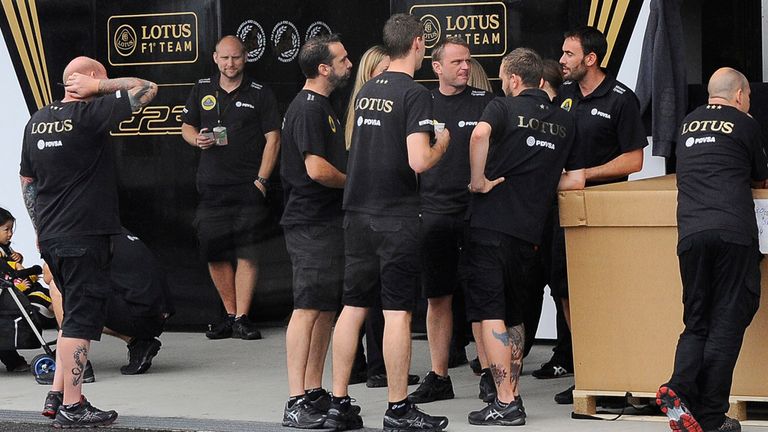 The Lotus team wait outside their closed garage in the Suzuka paddock