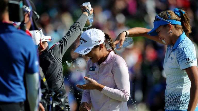 The teenage winner is given the traditional dousing of water on the final green