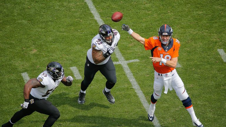 Quarterback Peyton Manning #18 of the Denver Broncos passes under pressure by outside linebacker Terrell Suggs #55 and defensive end Lawrence Guy