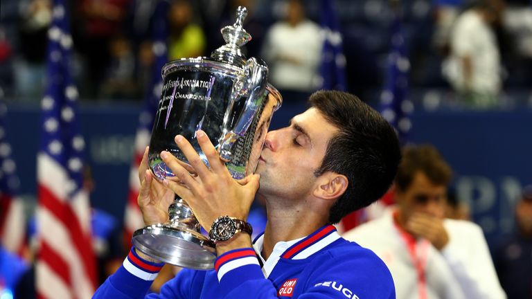 Novak Djokovic celebrates with the trophy after defeats Roger Federer during their Men's Singles Final