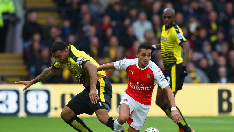 Alexis Sanchez and Troy Deeney compete for the ball