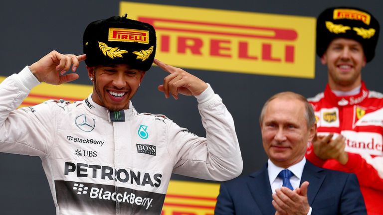 Lewis Hamilton celebrates on the podium next to President of Russia, Vladimir Putin, and Sebastian Vettel