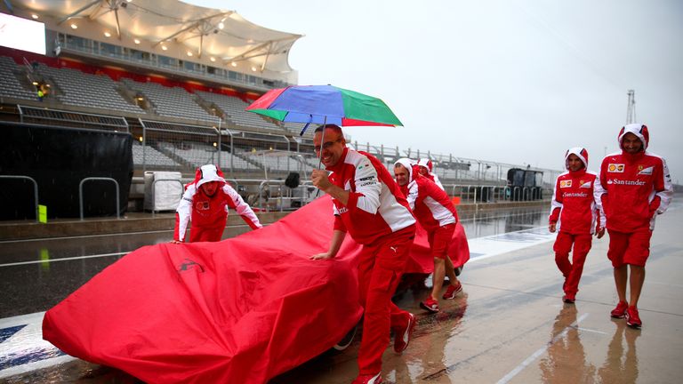 Ferrari mechanics keep their car covered from the elements as rain continues to batter Austin on Saturday