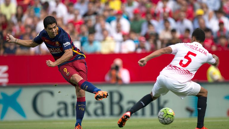 Luis Suarez (L) of FC Barcelona strikes the ball over Timothee Kolodziejczak (R) of Sevilla FC in La Liga 
