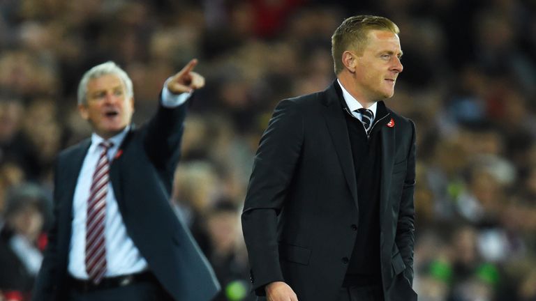 Mark Hughes manager of Stoke City (L) points towards the scoreboard as Garry Monk manager of Swansea City looks on