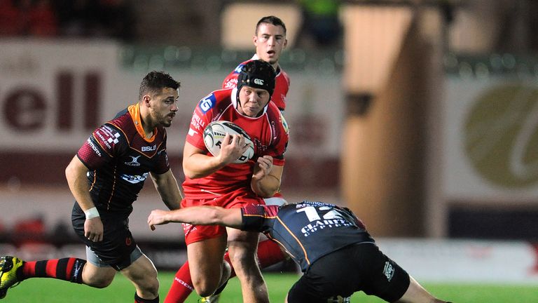 Scarlets' James Davies is tackled by Dragons' Adam Warren