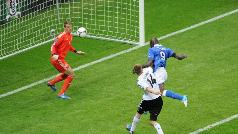 Mario Balotelli (R) of Italy jumps next to Holger Badstuber of Germany to score the opening goal past Manuel Neuer of Germany during Euro 2012 Semi-Final