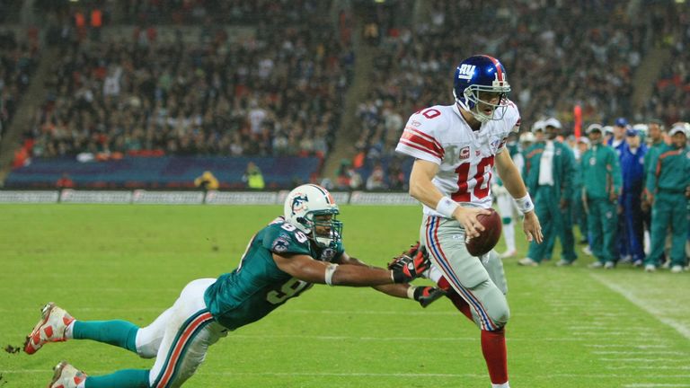 New York quarterback, Eli Manning #10 outpaces Jason Taylor #99 of the Dolphins to score the opening touchdown during the NFL Bridges