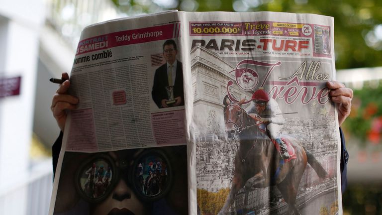 A racegoer reads the Paris Turf newspaper at Longchamp racecourse on October 04, 2015 in Paris, France