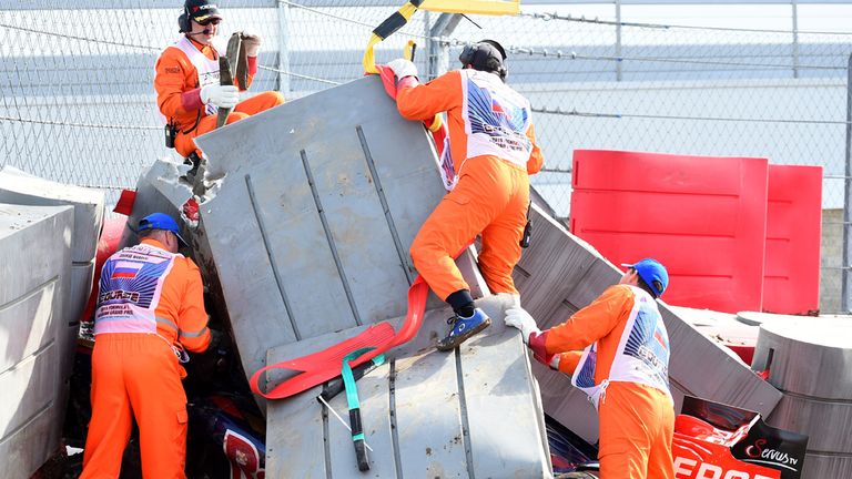 Marshals remove barriers from the top of Carlos Sainz's crashed car 