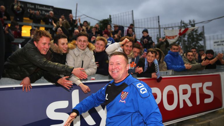 Andy Leese, the manager of Chesham United, celebrates with the travelling supporters after beating Bristol City