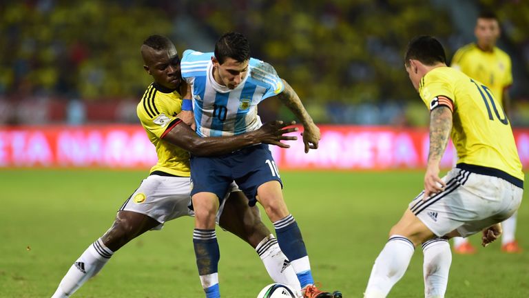 Argentina's Angel Di Maria (C) is marked by Colombia's Helibelton Palacios (L) 