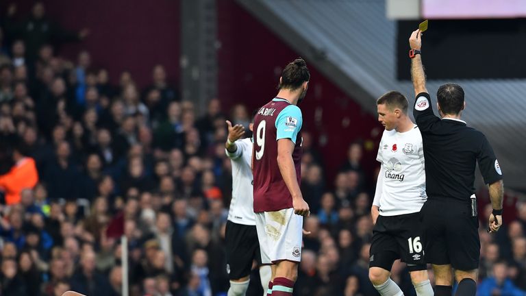 Everton's James McCarthy is booked while Dimitri Payet lies injured on the Upton Park pitch