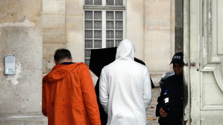 Karim Benzema (C), wearing a white hooded jersey, arrives at the police station in Versailles, southwest of Paris.