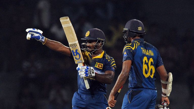 Sri Lankan batsman Kusal Perera (L) raises his bat to the crowd after reaching his half-century