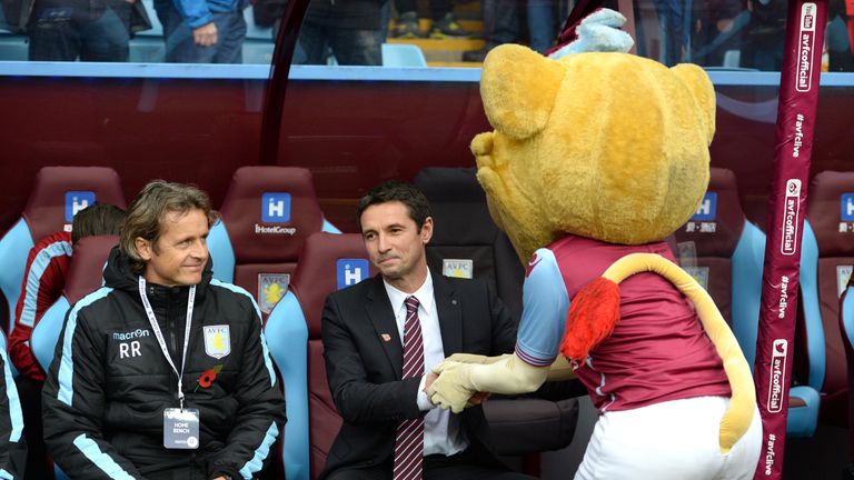 Aston Villa's new French manager Remi Garde (C) is greeted by the team mascot (R)