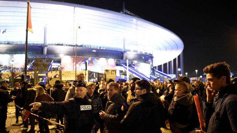 Football fans talk to a policeman securing an area outside the Stade de France on Friday night