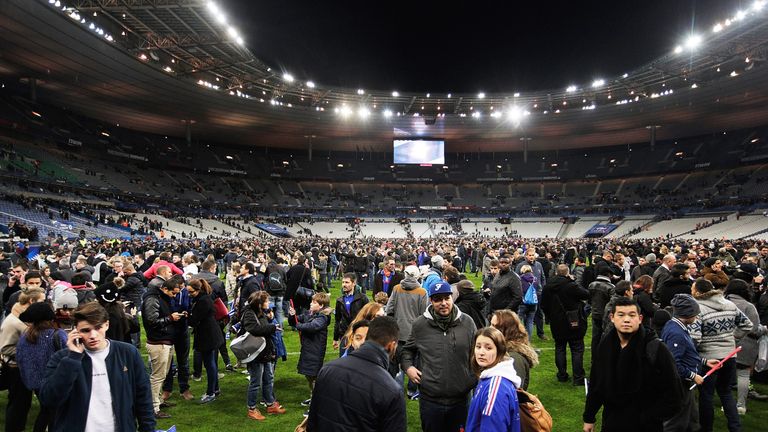 Spectators gather on the pitch after news of the bombing and terrorist attacks in Paris reaches the fans