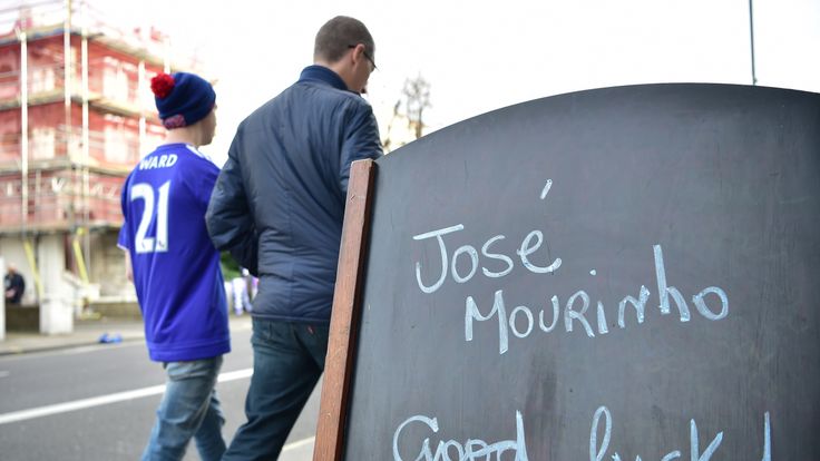 Football fans walk past a chalkboard wishing Chelsea's former manager Jose Mourinho good luck 