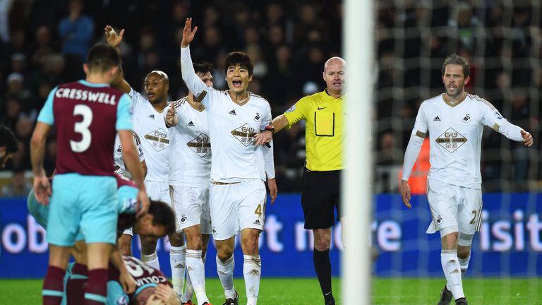 Swansea players appeal to referee Lee Mason after James Collins (ground) appeared to handle Ki Sung-yeung's shot