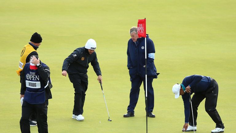 ST ANDREWS, SCOTLAND - JULY 18:  Louis Oosthuizen of South Africa and Tiger Woods of the United States pick up their balls on the 13th green as play is sus