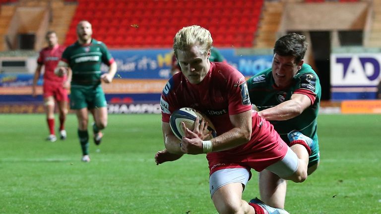 Aled Davies of Scarlets dives over the line for his try under pressure from Freddie Burns of Leicester