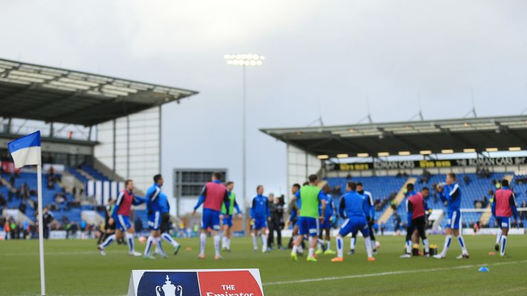 Colchester United players warm up in front of the FA Cup sign prior to the FA Cup Fourth Round match v Tottenham Hotspur, Weston Homes Community Stadium
