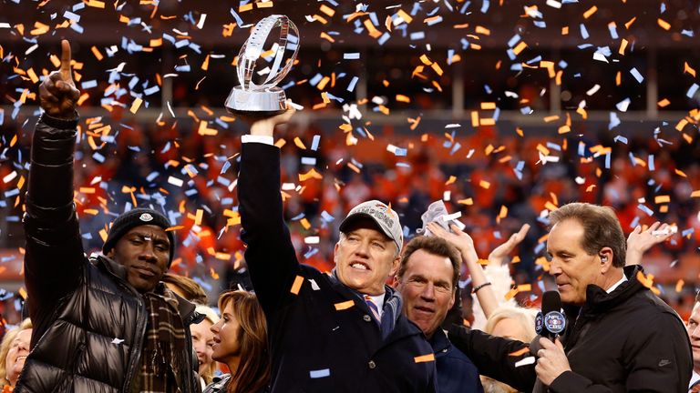 General Manager and Executive Vice President of Football Operation for the Denver Broncos John Elway holds up the Lamar Hunt Trophy