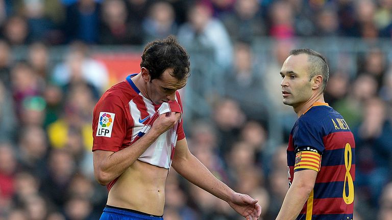 Atletico Madrid's Uruguayan defender Diego Godin (L) passes by Barcelona's midfielder Andres Iniesta as he leaves the pitch after being sent off