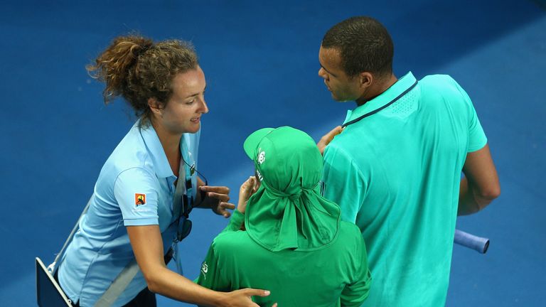 Jo-Wilfried Tsonga of France escorts a ball-girl off the court 