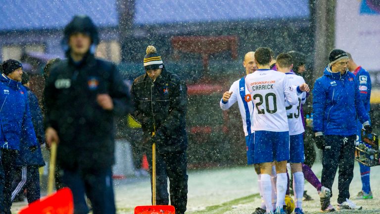 Kilmarnock players chatted as the groundsmen rushed on to the pitch to clear the lines of snow during the game 