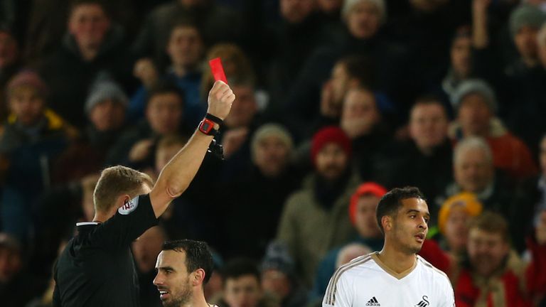 Kyle Naughton (R) of Swansea City is shown a red card by referee Graham Scott (L)