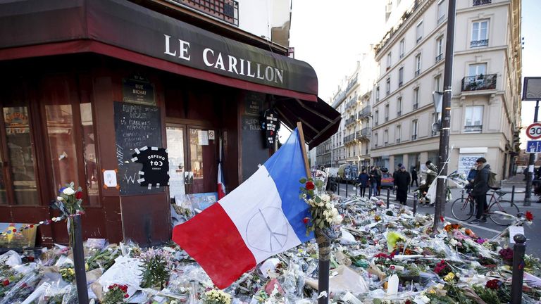 A French flag flies over flowers, candles and messages in tribute to victims outside "Le Carillon" restaurant a week after a series of deadly attacks in the French capital Paris