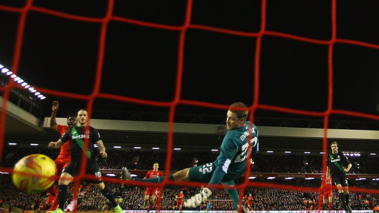 Marko Arnautovic of Stoke City (2L) shoots past goalkeeper Simon Mignolet of Liverpool to score their first goal during their league cup semi final